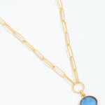 Gold necklace with a blue pendant on a white background