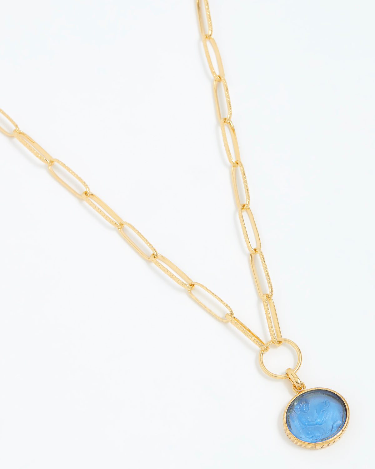 Gold necklace with a blue pendant on a white background