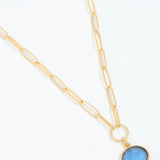 Gold necklace with a blue pendant on a white background