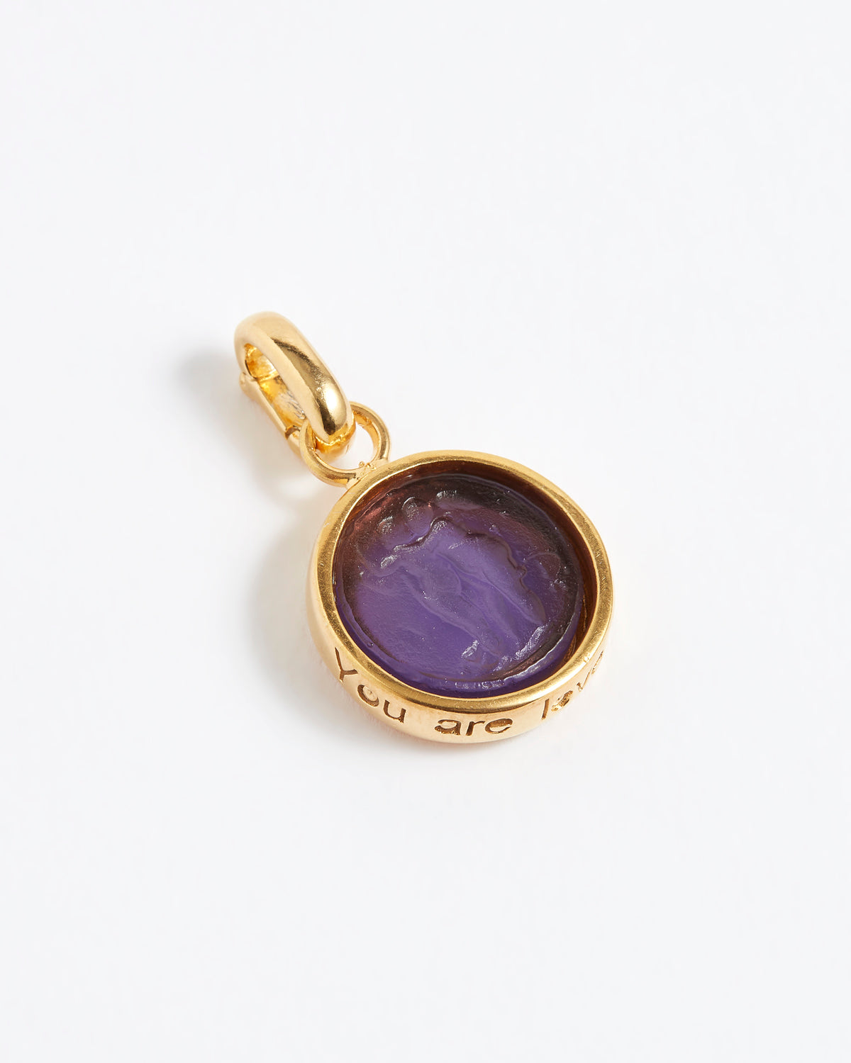 Gold pendant with purple stone on a white background