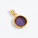 Gold pendant with purple stone on a white background