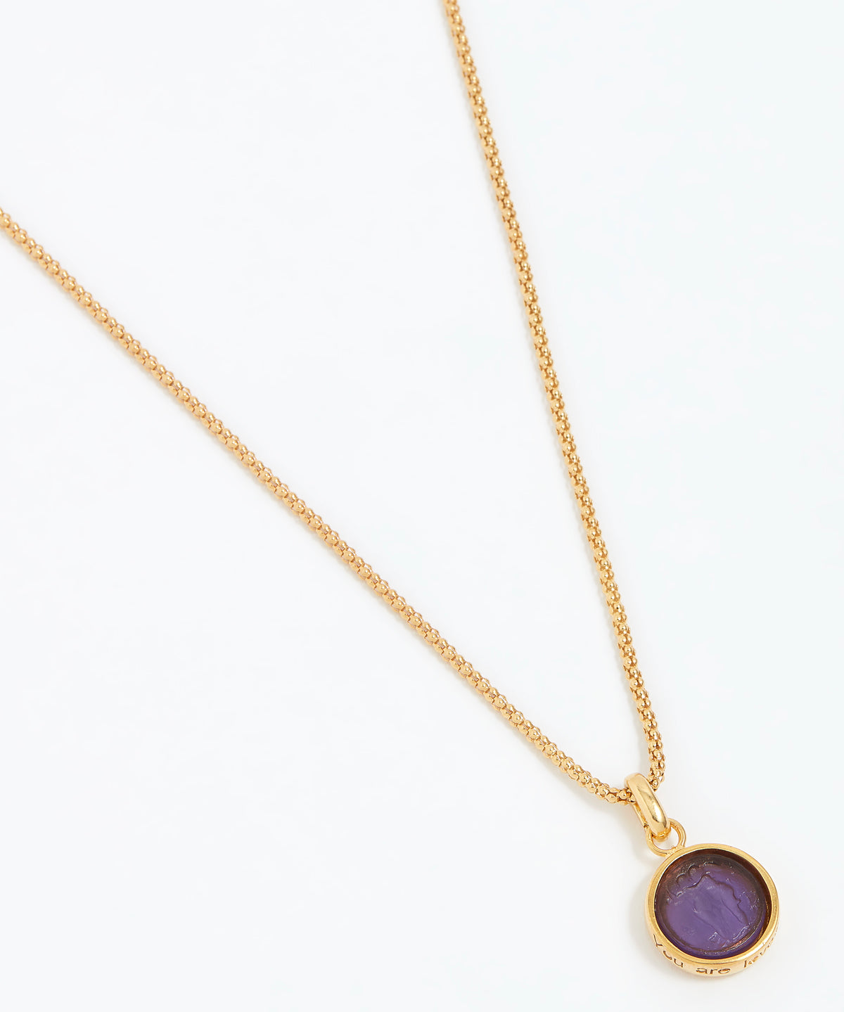 Gold necklace with a purple pendant on a white background