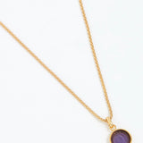 Gold necklace with a purple pendant on a white background