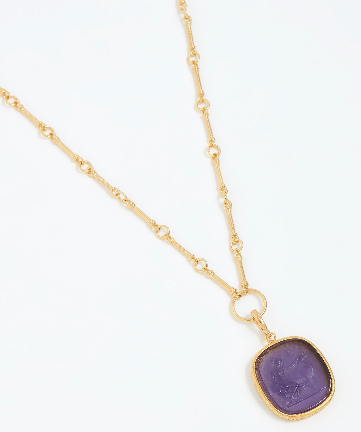Gold necklace with a purple pendant on a white background