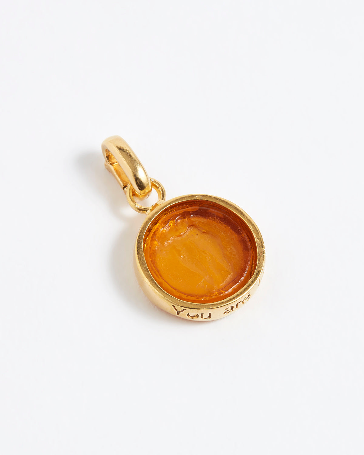 Gold pendant with a yellow stone on a white background