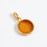 Gold pendant with a yellow stone on a white background