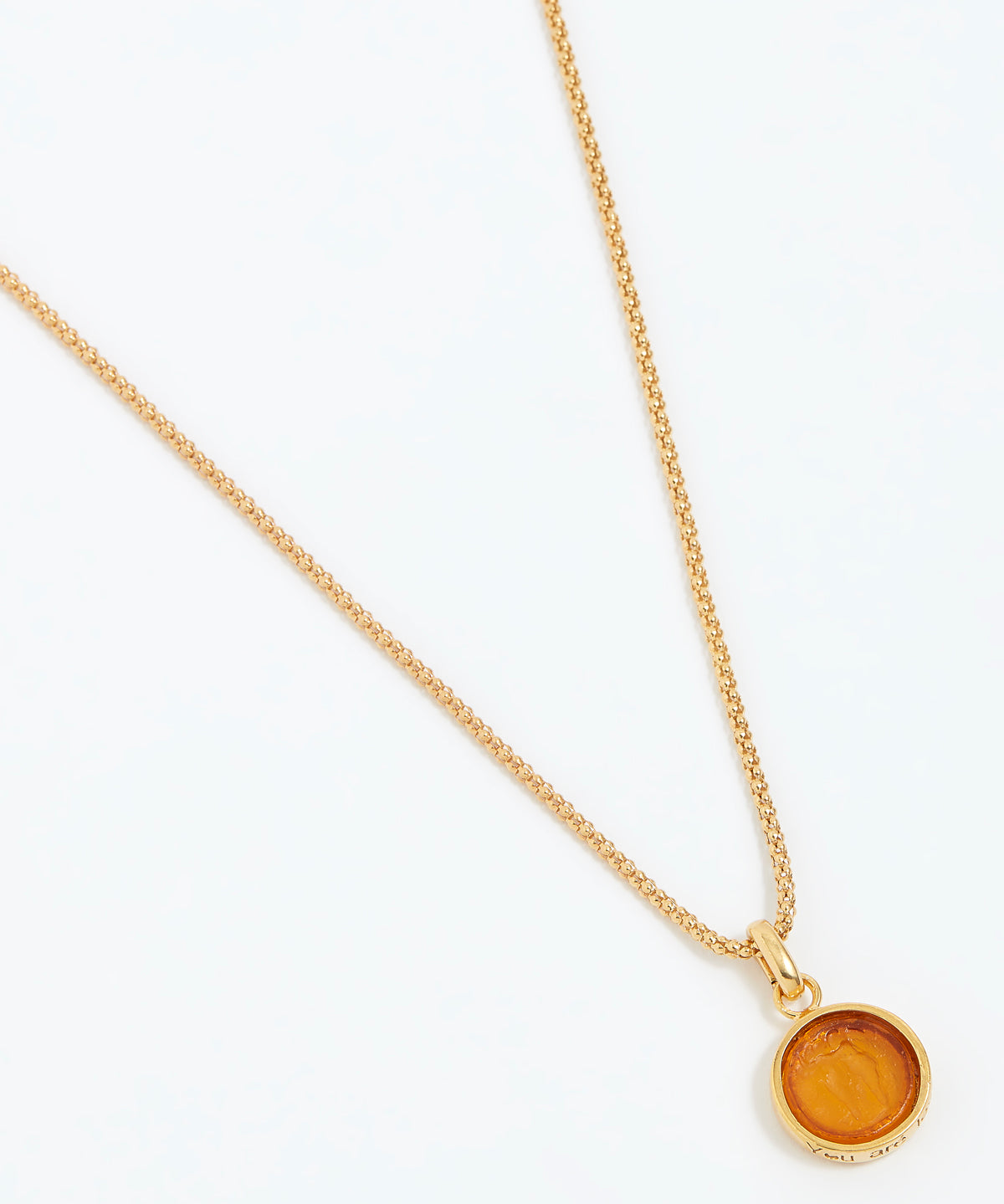 Gold necklace with a round pendant on a white background