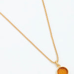 Gold necklace with a round pendant on a white background