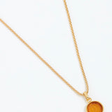 Gold necklace with a round pendant on a white background