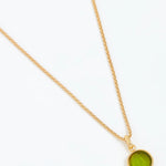 Gold necklace with a green pendant on a white background
