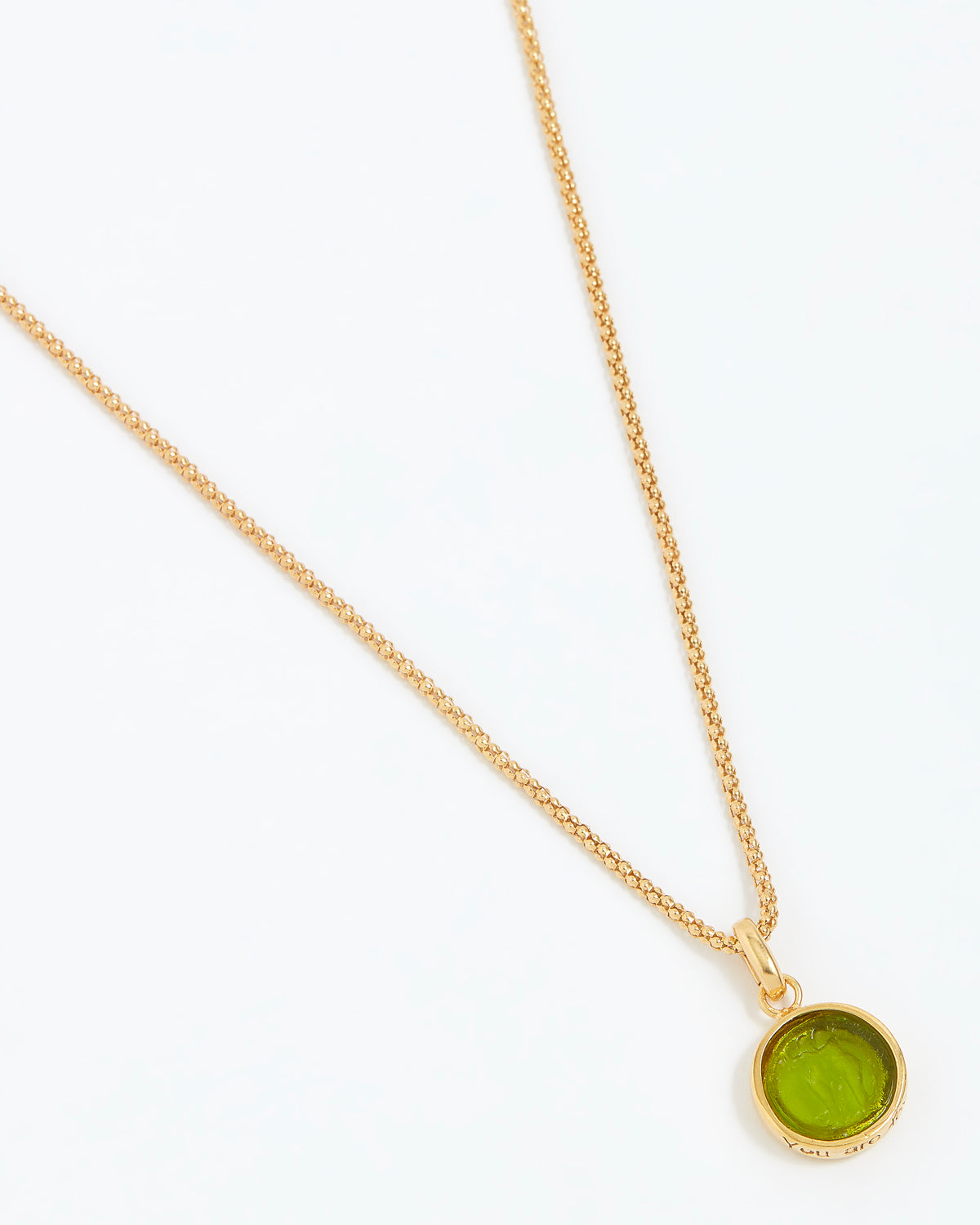 Gold necklace with a green pendant on a white background