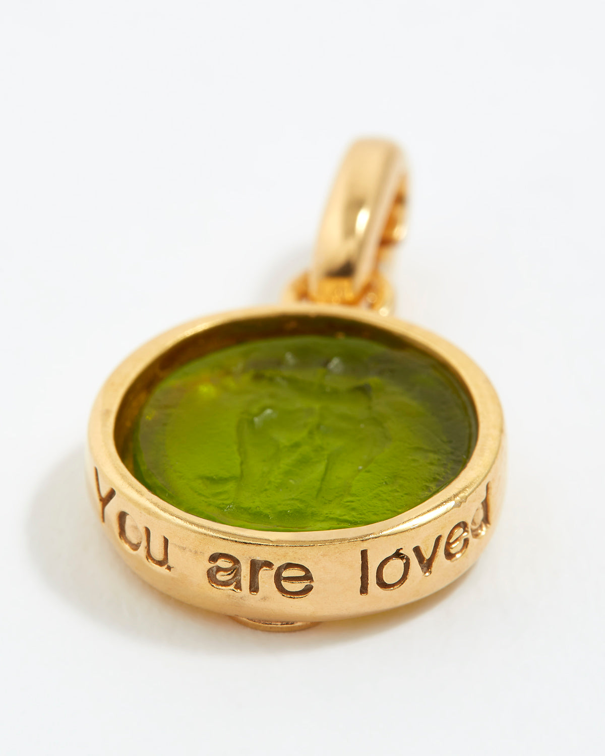 Gold pendant with green stone and 'You are loved' engraving on a white background
