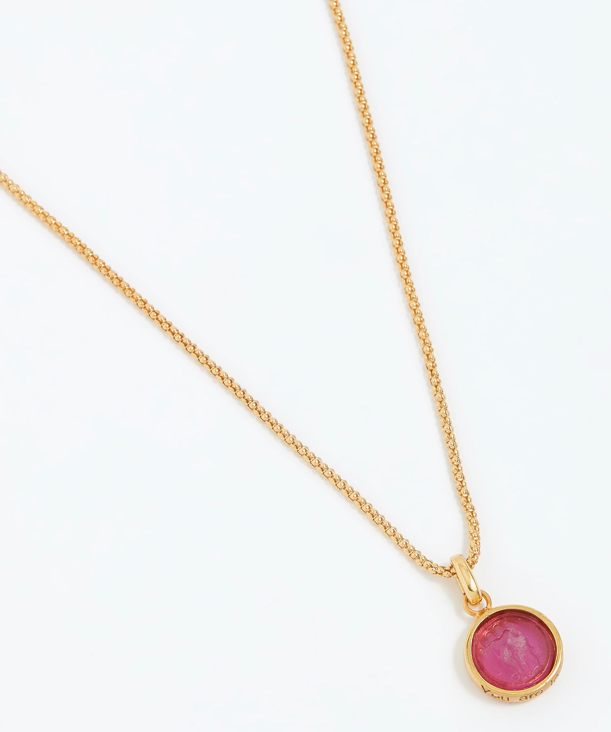 Gold necklace with a pink gemstone pendant on a white background