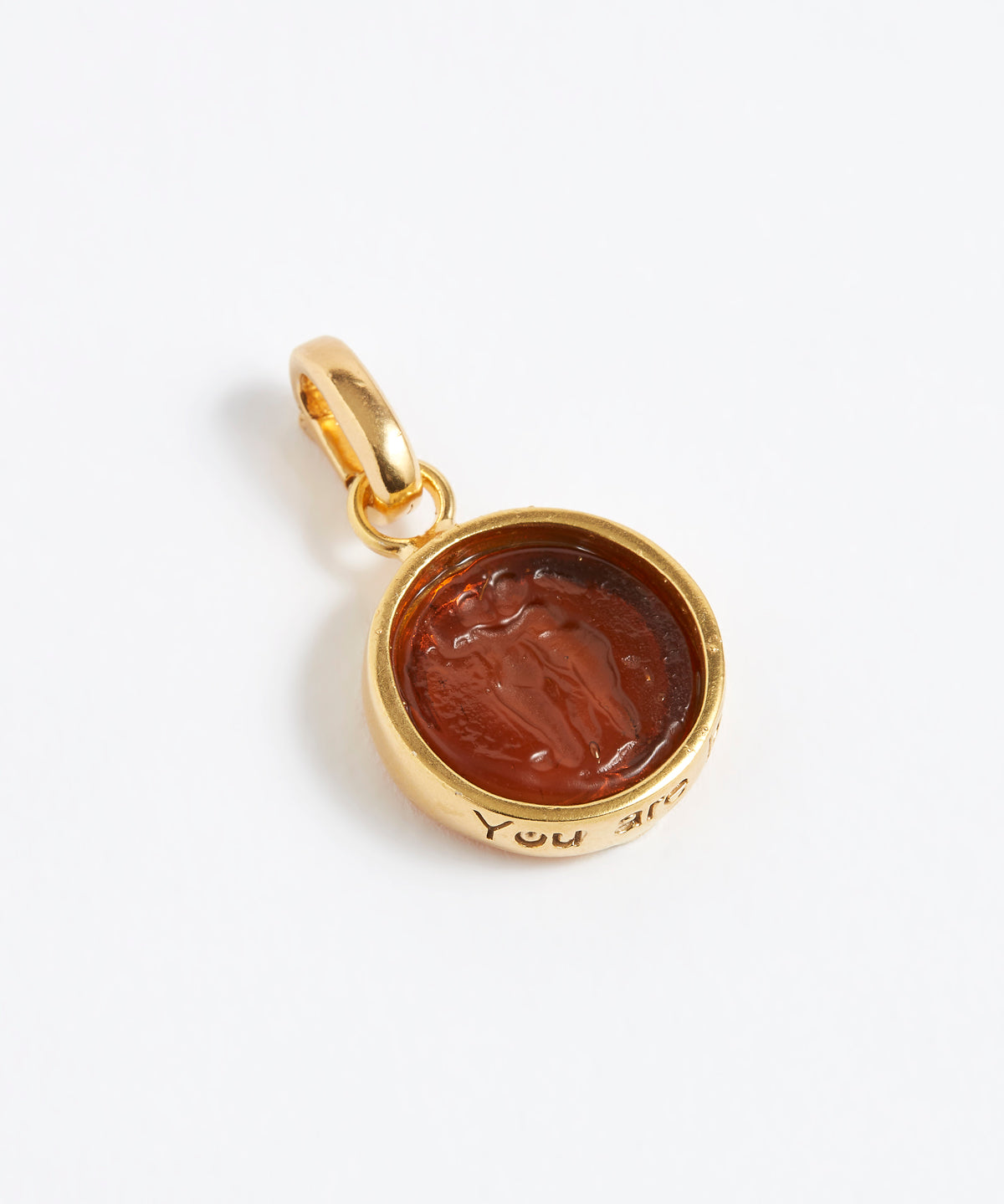 Gold pendant with a brown stone on a while background