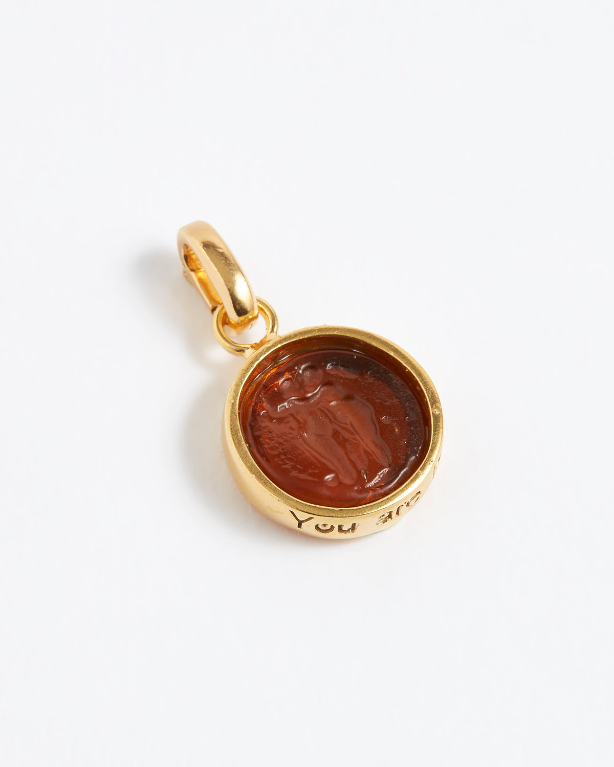 Gold pendant with a brown stone on a while background