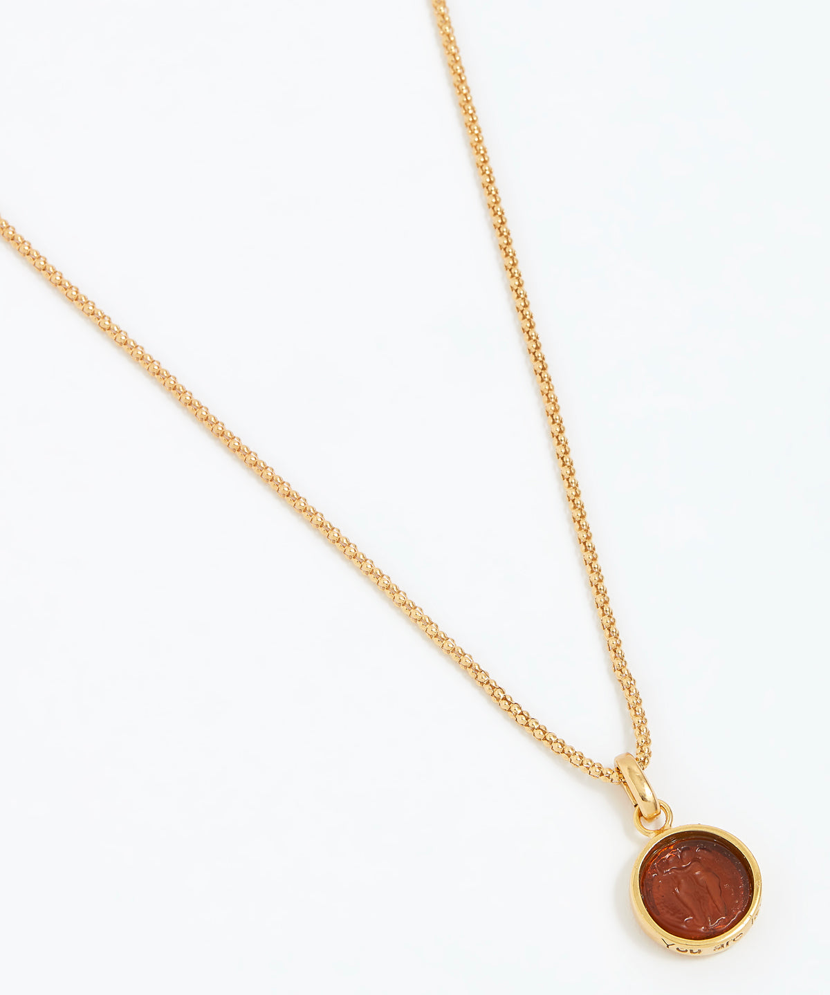 Gold necklace with a round pendant on a white background