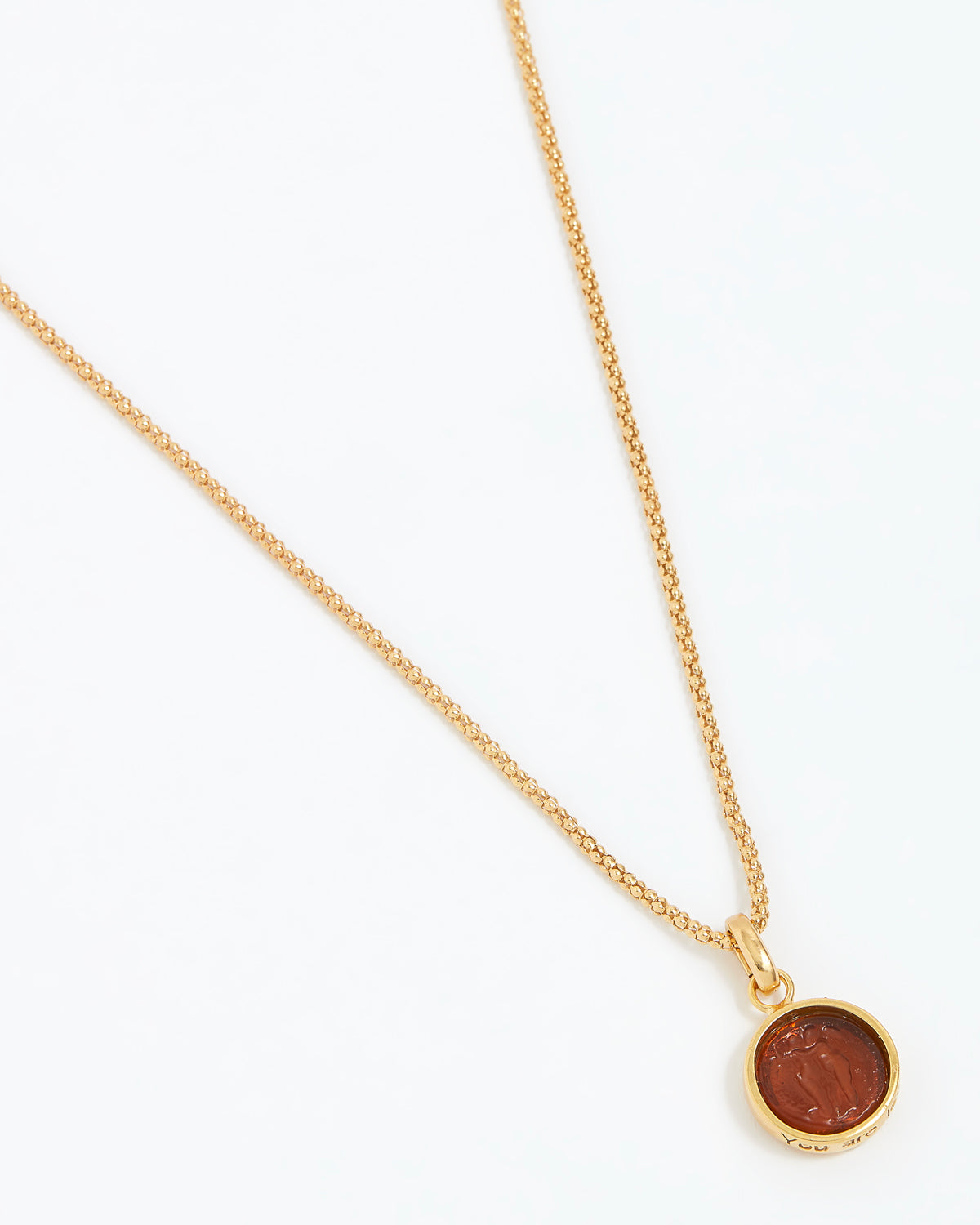 Gold necklace with a round pendant on a white background