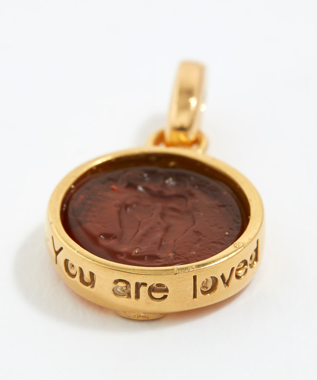 Gold pendant with a brown center and 'You are loved' engraving on a white background