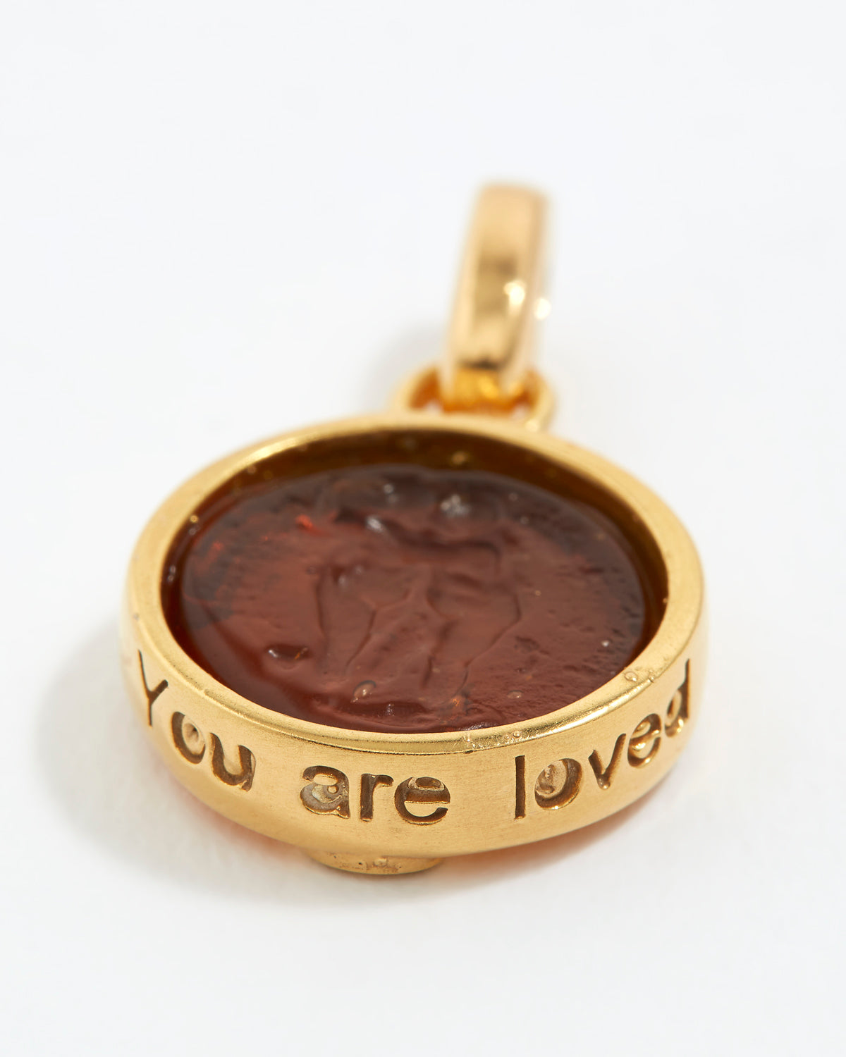 Gold pendant with a brown center and 'You are loved' engraving on a white background
