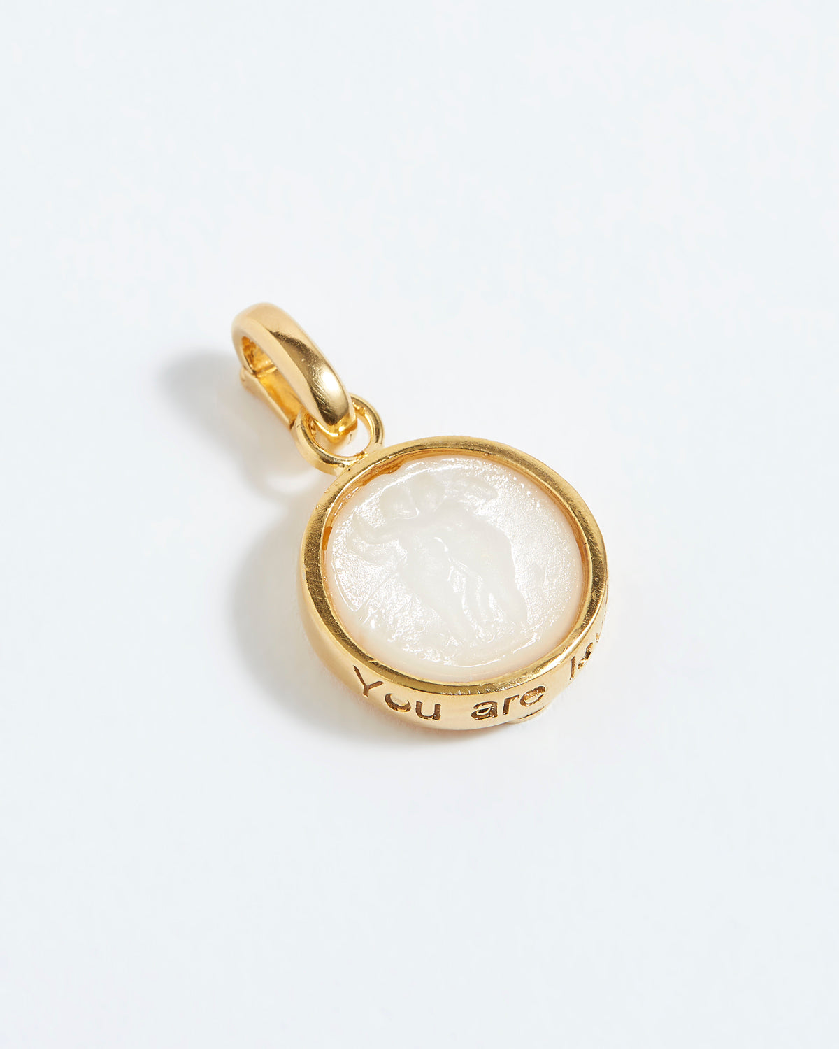 Gold pendant with a white stone on a white background