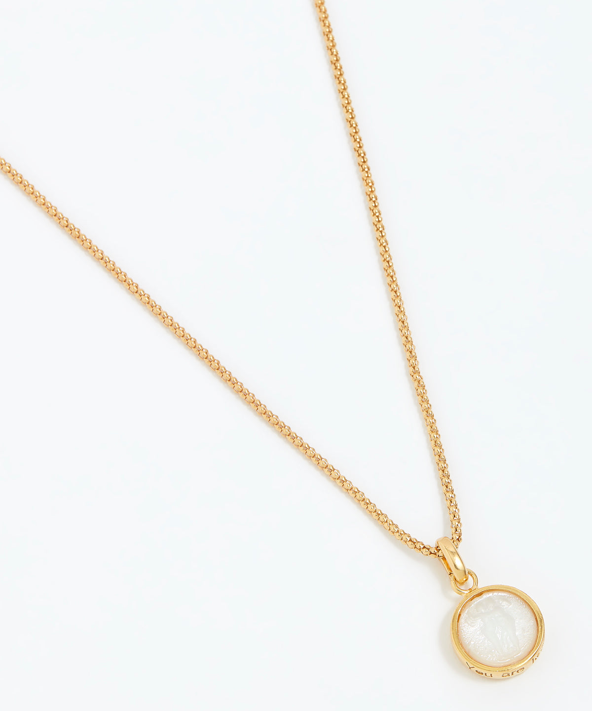 Gold necklace with a round pendant on a white background