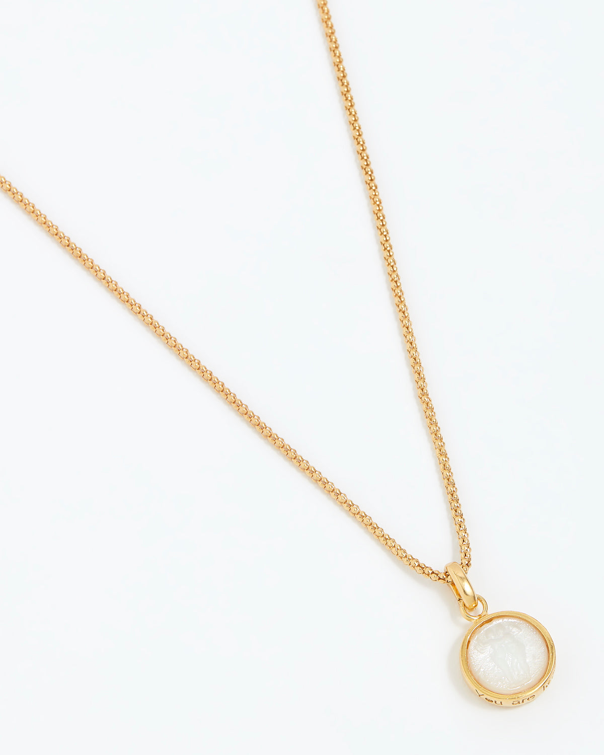 Gold necklace with a round pendant on a white background