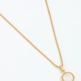 Gold necklace with a round pendant on a white background