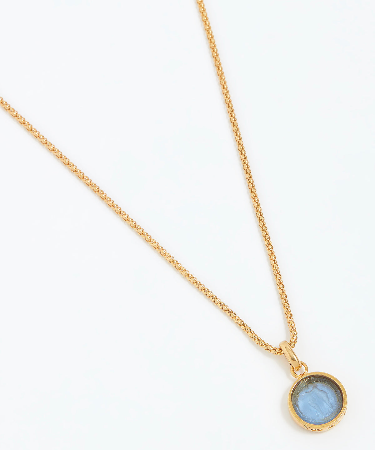Gold necklace with a blue gemstone pendant on a white background