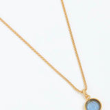 Gold necklace with a blue gemstone pendant on a white background