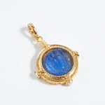 Gold pendant with a blue gemstone on a white background