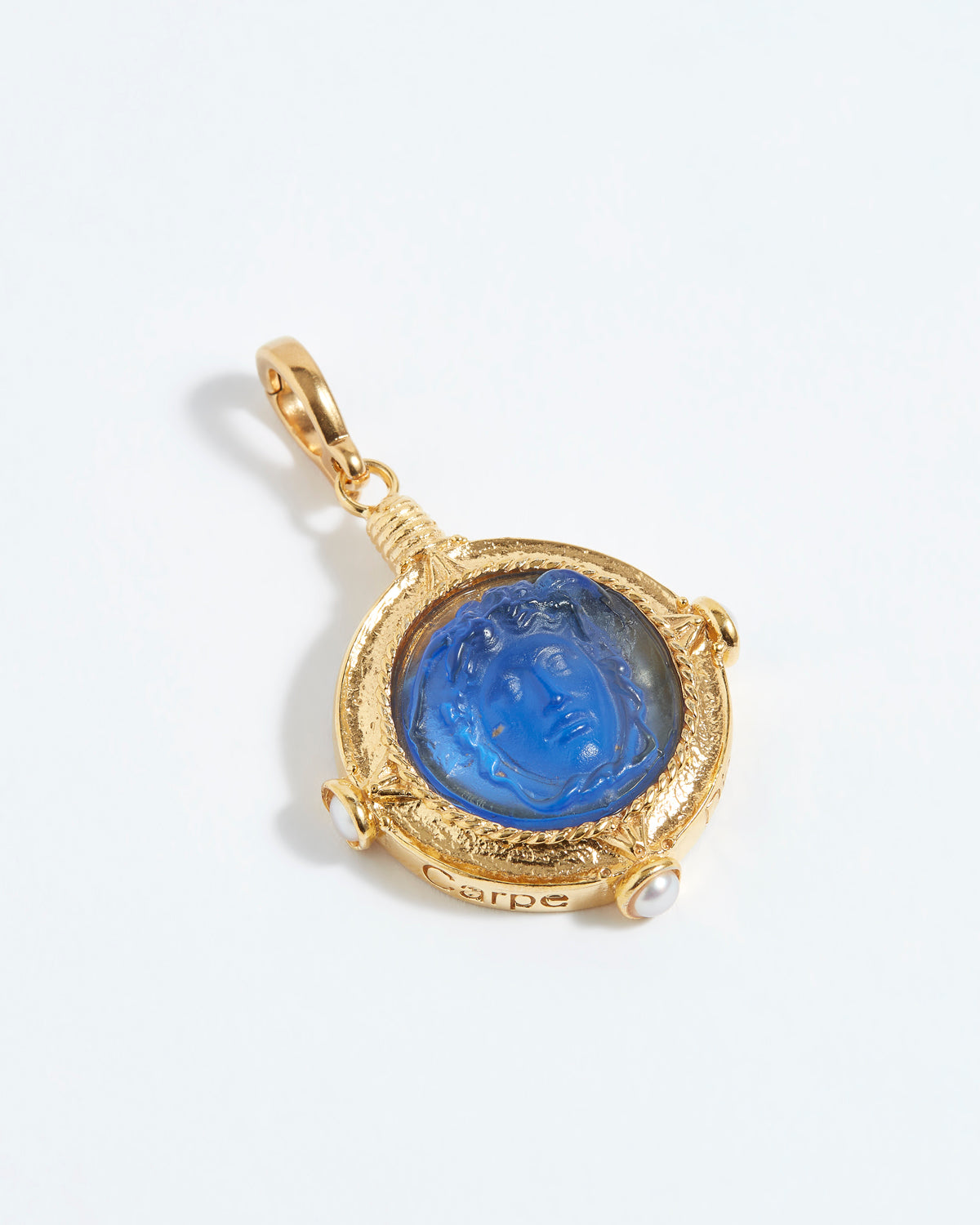 Gold pendant with a blue gemstone on a white background