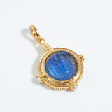 Gold pendant with a blue gemstone on a white background