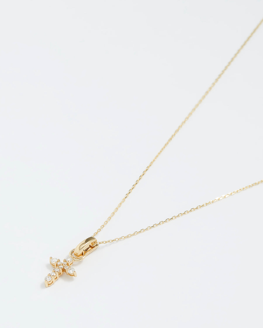 small cross charm made of gold and diamonds, to be worn on an earring or necklace, product shot on a necklace chain