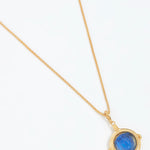 Gold necklace with a blue gemstone pendant on a white background