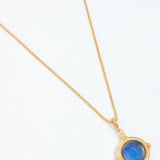 Gold necklace with a blue gemstone pendant on a white background