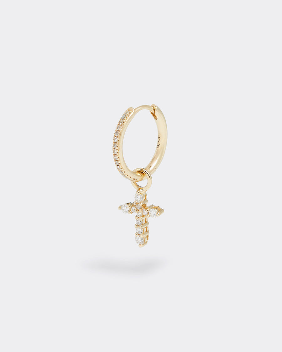 small cross charm made of gold and diamonds, to be worn on an earring or necklace, product shot on a hoop earring