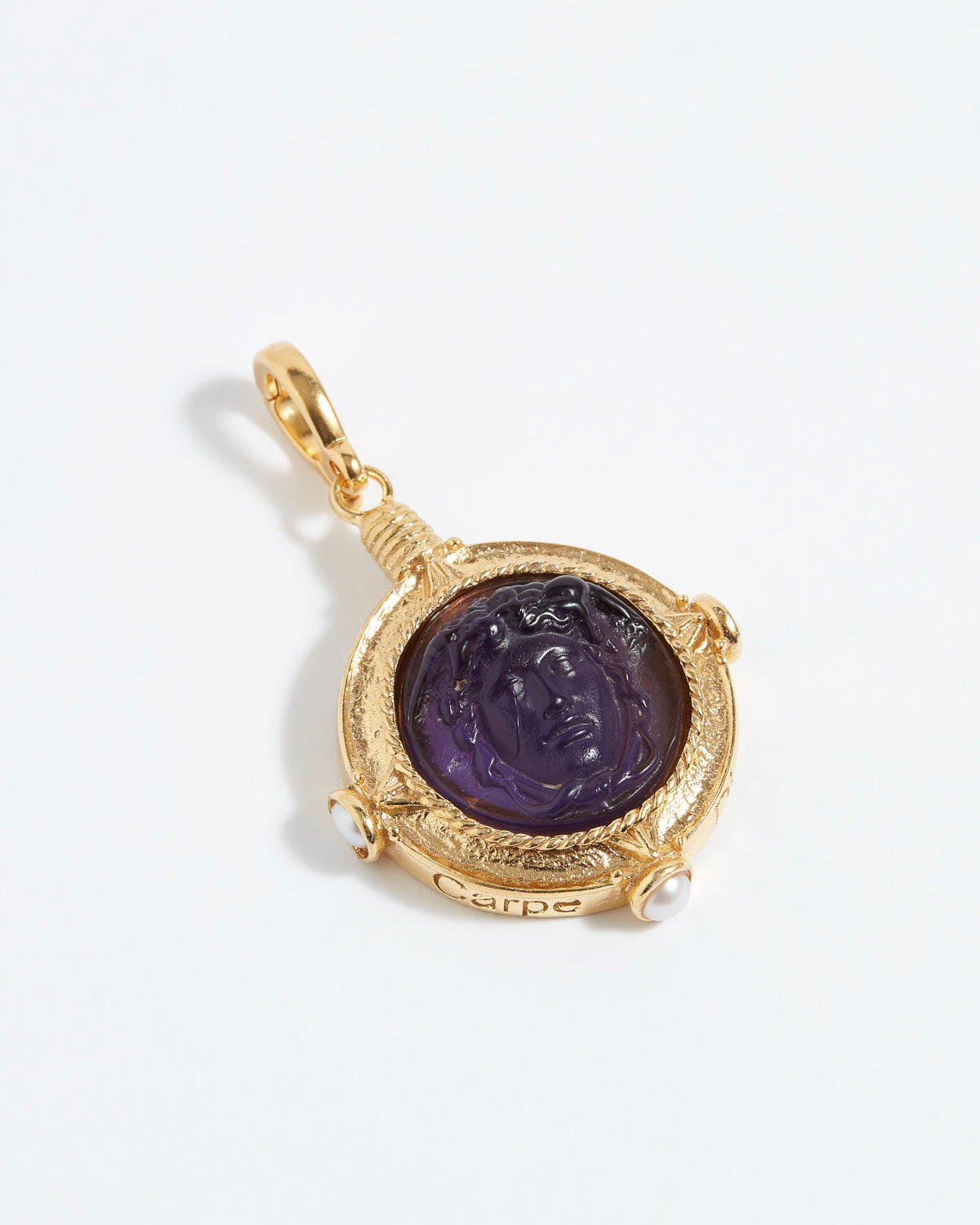 Gold pendant with a purple stone on a white background