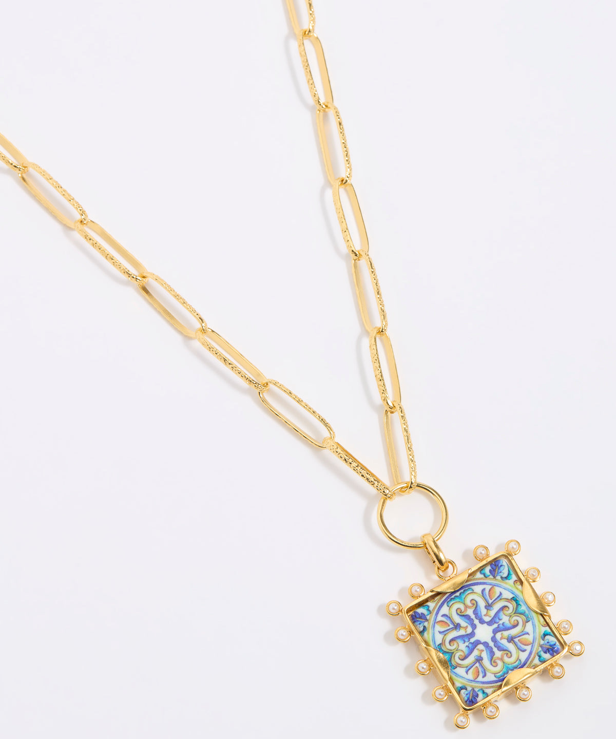 Decorative pendant with blue and gold design on a square tile with mini pearl edging  hung from a chinky gold chain on a white background