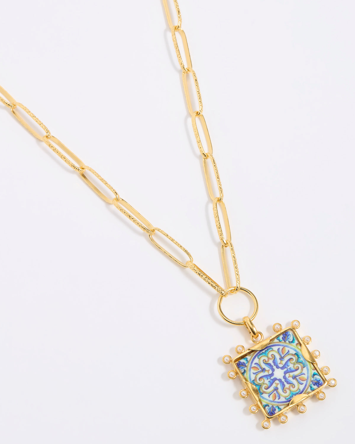 Decorative pendant with blue and gold design on a square tile with mini pearl edging  hung from a chinky gold chain on a white background
