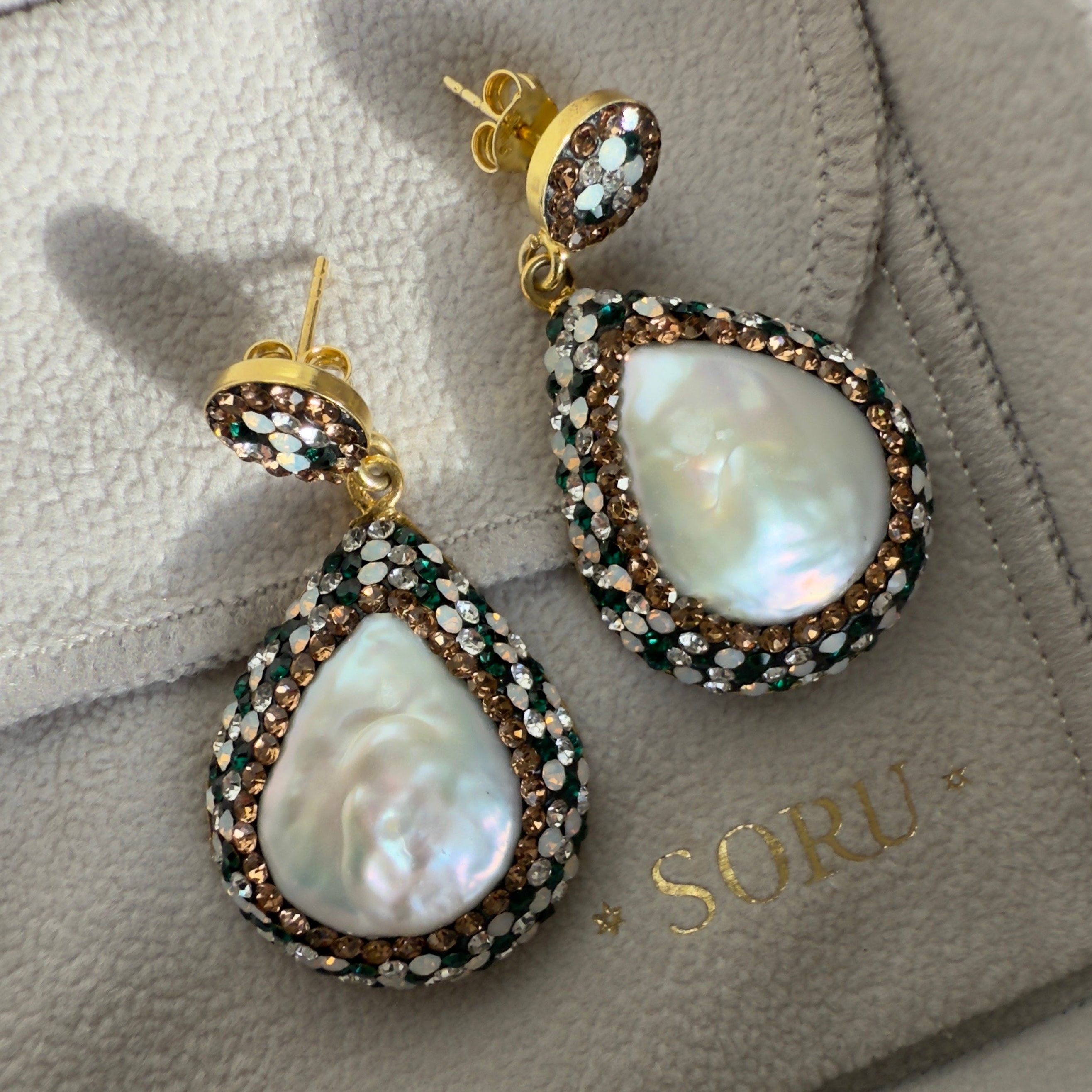 Pair of pearl earrings on a branded jewelry box