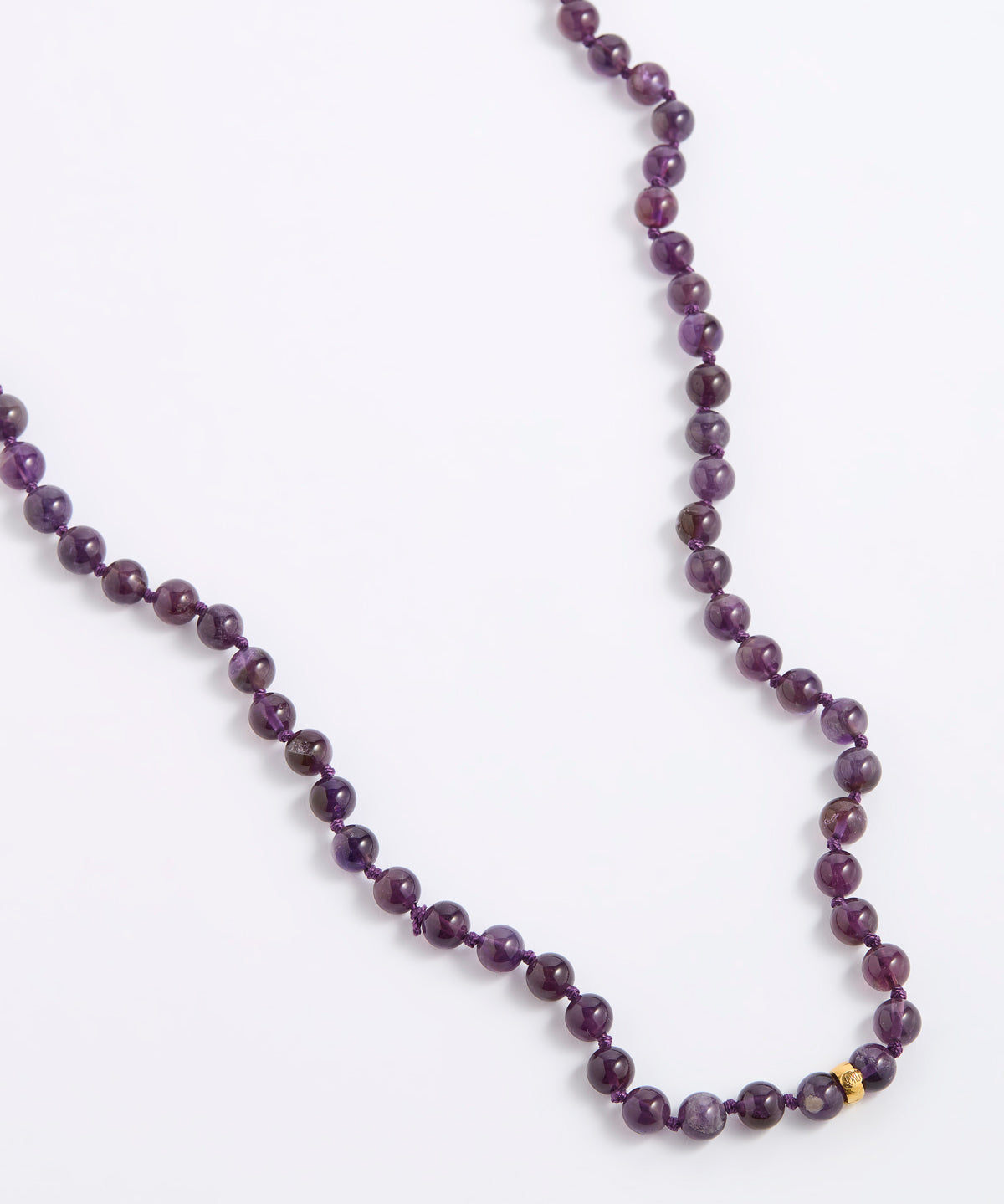 A beaded necklace made of dark purple, round gemstone beads with a small gold spacer bead, displayed on a clean white background.