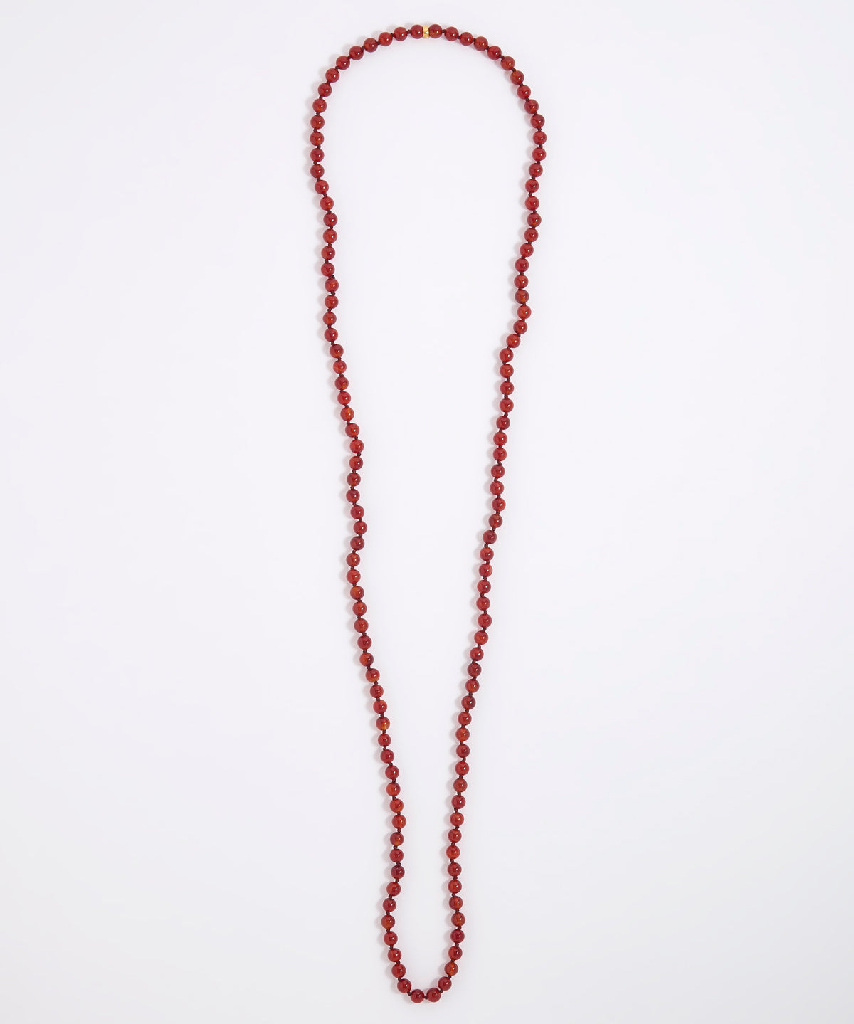 A long beaded necklace made of small round red beads, laid flat on a plain white background.