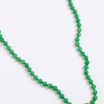 A green agate beaded necklace made of small, round, polished beads with a tiny gold spacer accent, displayed on a white background.