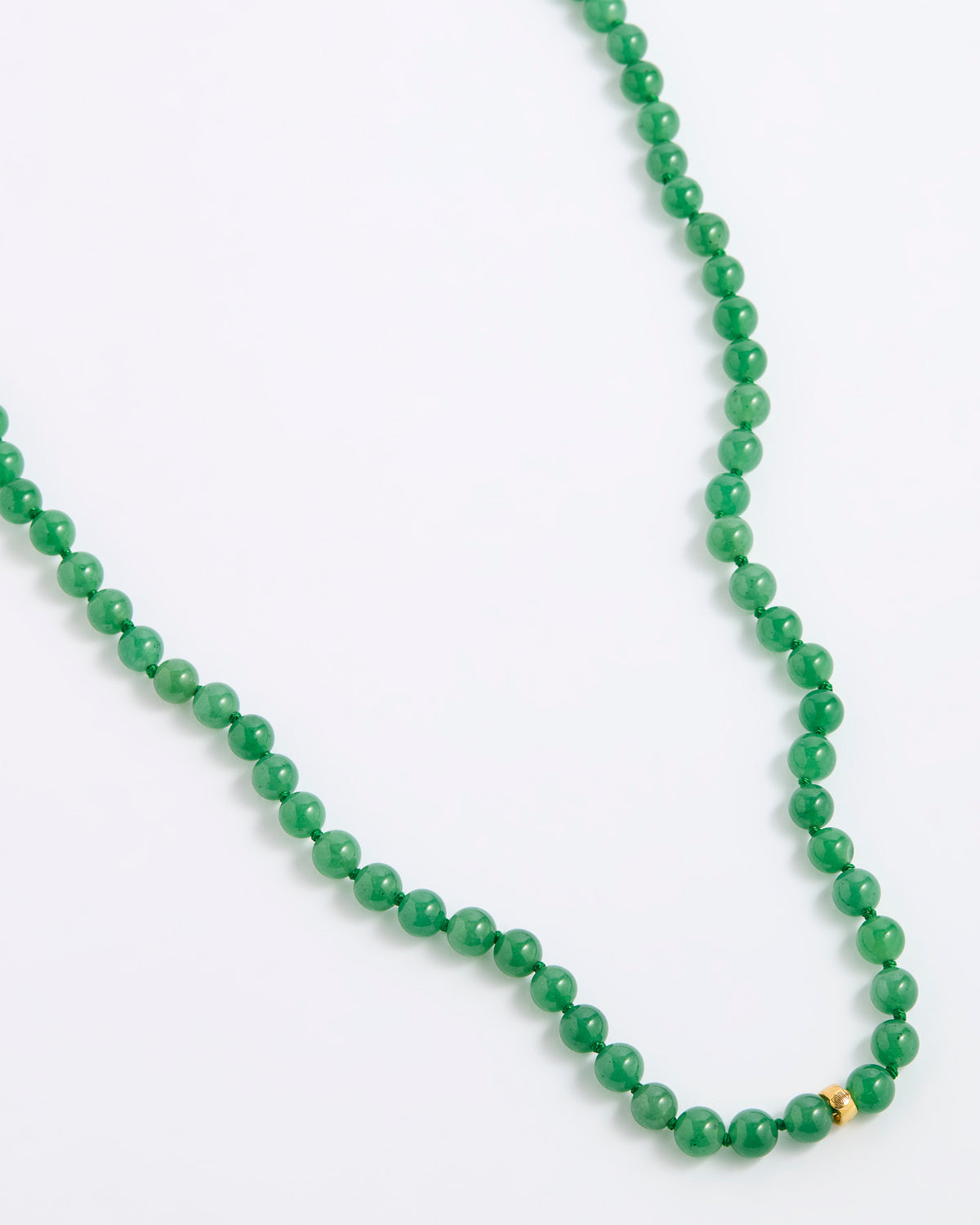 A green agate beaded necklace made of small, round, polished beads with a tiny gold spacer accent, displayed on a white background.