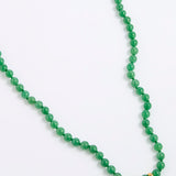 A green agate beaded necklace made of small, round, polished beads with a tiny gold spacer accent, displayed on a white background.