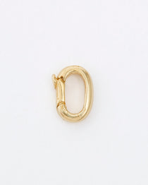 Gold clasp used for charm necklaces on grey background