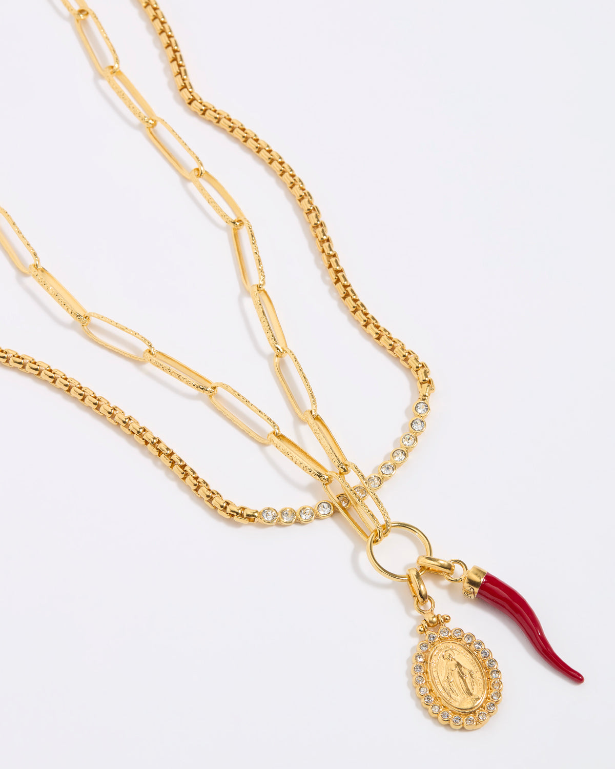 Gold necklace with a pendant and red accent on a white background