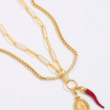 Gold necklace with a pendant and red accent on a white background