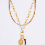 Gold chain necklace set with red cornicello and crystal pendant charms on a white background
