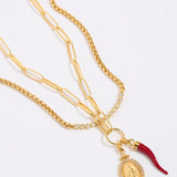 Gold necklace with a pendant and red accent on a white background